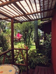 a patio with a wooden pergola and a pink flower at Pousada Canto Bella Terra in Ilhabela