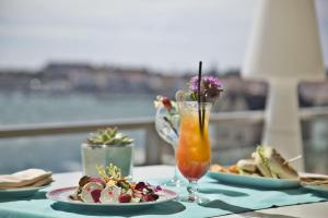 a table with two plates of food and a drink at Hotel Cascais Miragem Health & Spa in Cascais