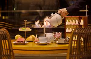 a person holding a pot over a table with tea cups at Hotel Cascais Miragem Health & Spa in Cascais