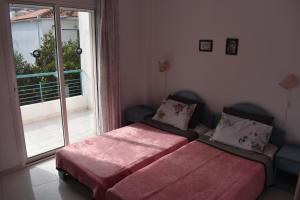 a bedroom with two beds in front of a window at Niki Apartments in Polykhrono