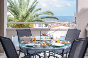 una mesa con comida en el balcón con vistas al océano en Sevach Apartments, en Kalamaki