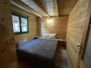 Habitación con cama en una cabaña de madera en Fenyőtoboz kulcsosház, en Izvoare