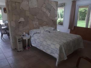 a bedroom with a bed and a stone wall at Preciosa casa loft ideal parejas en Barrio Privado in Balneario Mar Chiquita