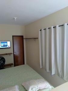 a bedroom with a bed and a curtain and a television at Kitnet 2,vista fantastica in Cabo de Santo Agostinho