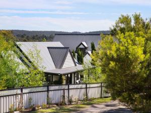 ein Haus mit einem weißen Zaun und Bäumen in der Unterkunft Cottage 4A - sweet retreat with spa in Daylesford in Daylesford