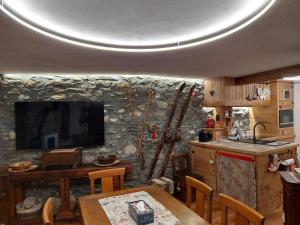 kuchnia ze stołem i telewizorem na kamiennej ścianie w obiekcie Maison du ski LTH - CIR -VDA-LA THUILE-N0011 w mieście La Thuile