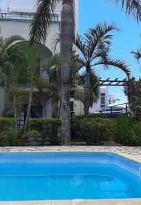 a blue swimming pool in front of a house with palm trees at Blue Sky Villa in Grand-Baie