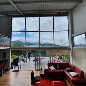 a living room with a red couch and a large window at Finca Prometeo - Lago Calima in Calimita