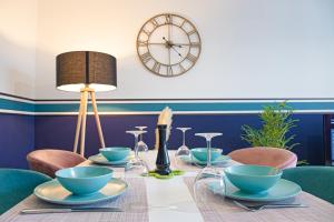 una mesa con cuencos y sillas azules y un reloj en Le petit Panam - Appartement privé de 45 m2 - 2 à 4 personnes - Parking privé, en Metz