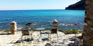 a table and two chairs sitting on the beach at Pilion-Unique House at the Aegean Sea in Keramídhion