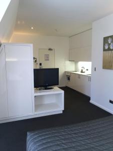 a living room with a tv and a white kitchen at The Social Hotel, Sydney in Sydney