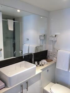 a white bathroom with a sink and a mirror at The Social Hotel, Sydney in Sydney