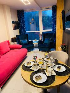 - un salon avec une table et un canapé rouge dans l'établissement Apartament SPA 52 Resort Kozubnik blisko Szczyrk- 5D Apartamenty, à Porąbka