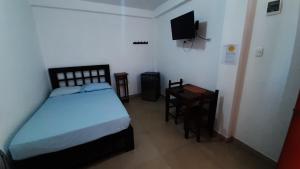 1 dormitorio con cama, mesa y TV en Bungalows Rupay Wasi en Los Órganos