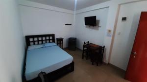 ein Schlafzimmer mit einem Bett und einem TV. in der Unterkunft Bungalows Rupay Wasi in Los Órganos