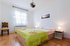 a white bedroom with a bed and a chair at Apartment Josip in Senj