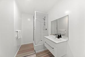 baño blanco con ducha y lavamanos en Hilltop House - Taupo, en Taupo