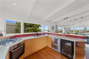 a kitchen with a stove top oven next to a living room at Hilltop House - Taupo in Taupo