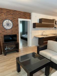 a living room with a couch and a clock on the wall at Exclusive 9- Urban apartments in Kochani