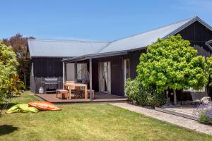 a black house with a patio and a yard at The Escape in Martinborough