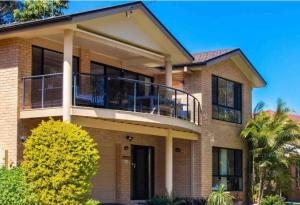 a large house with a balcony on top of it at 4 Bedroom modern house opposite Wallis Lake in Forster