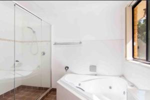 a white bathroom with a tub and a shower at 4 Bedroom modern house opposite Wallis Lake in Forster