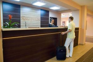 a man standing at a reception desk with a suitcase at Ilmar City Hotel in Kazan