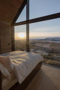 a bed in a room with a large window at Iceland Lakeview Retreat in Selfoss