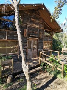 a log cabin with a porch and a tree at Cabañas Rústicas Pucón Río Trancura in Pucón