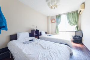 a hotel room with two beds and a window at Hotel Villa Dogo in Matsuyama