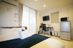 1 dormitorio con cama, nevera y escritorio en ラ・ルーチェ東仲宗根, en Isla Miyako