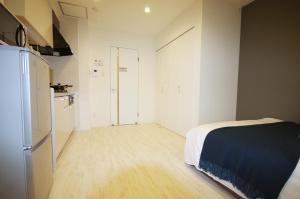 a room with a kitchen with a bed and a refrigerator at ラ・ルーチェ東仲宗根 in Miyako Island