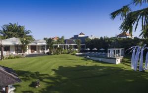a yard with green grass and palm trees and houses at Pure Villa Bali by Nagisa Bali in Dalung