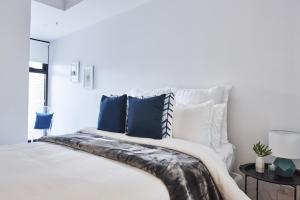 墨尔本Mega Style Apartments St Kilda的白色卧室配有一张带蓝色枕头的大床