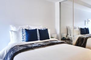 墨尔本Mega Style Apartments St Kilda的卧室里有一张床，上面有蓝色枕头和一面镜子 更多8张照片