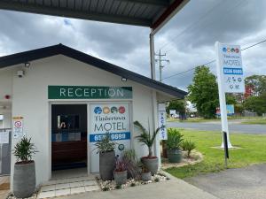 een wit gebouw met een bord ervoor bij Timbertown Motel in Wauchope