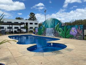 een zwembad met een muurschildering aan de zijkant van een gebouw bij Timbertown Motel in Wauchope