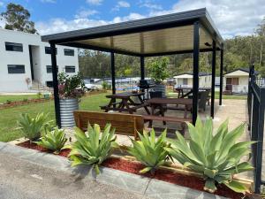 a pavilion with a picnic table and benches in a park at Timbertown Motel in Wauchope