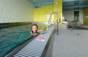 a young child is in a swimming pool at Horský Hotel Friesovy Boudy in Strážné