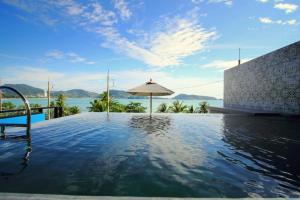 una piscina con sombrilla y agua en See Sea Villa Phuket SHA, en Patong Beach