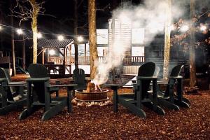 a group of chairs around a fire pit at night at Wine Time 5 Bedroom Shuffleboard Hot Tub Fire Pit Play Set in Broken Bow