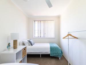 a white bedroom with a bed and a window at Fingal Court 2 2 Lentara St in Fingal Bay