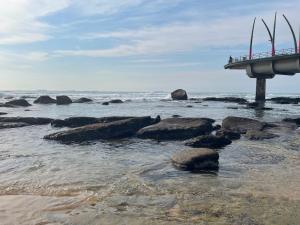 a bridge over a beach with rocks and the ocean at The Studio on Cordia DSTV WIFI 2km from Umhlanga Beach in Durban