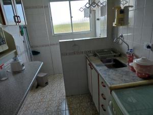 a small kitchen with a sink and a window at Apartamento na Praia da Enseada - Guarujá in Guarujá