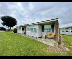 a house with a bench in front of it at Chalet hemsby in Great Yarmouth