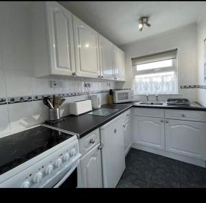 uma cozinha branca com armários brancos e um lavatório em Chalet hemsby em Great Yarmouth