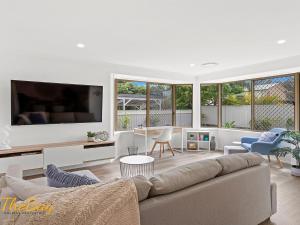 een woonkamer met een bank en een tv bij Waves on Whitesands in Fingal Bay