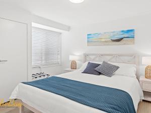 a white bedroom with a bed and a window at Waves on Whitesands in Fingal Bay