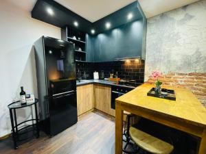 a kitchen with a black refrigerator and a wooden table at Villa 3 in Mediaş