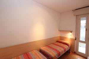 um pequeno quarto com uma cama e uma janela em Beautiful villa just few steps from the beach em Bibione